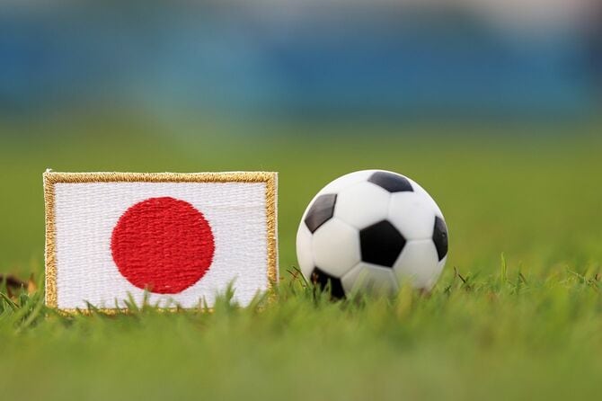 スタジアムの芝生に映る日本の国旗とサッカーボール