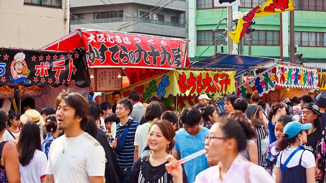 人々で混雑する祭りの日の屋台が並んだ通り