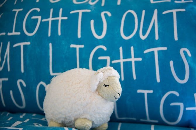 青いベッドシーツと羊のぬいぐるみ