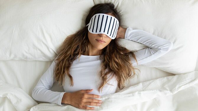 アイマスクをしてベッドで眠る女性