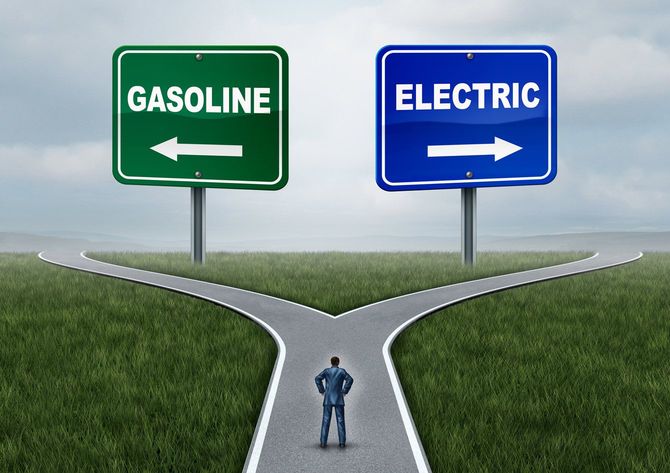 ガソリンと電気に分岐した道で悩んでいる人の絵