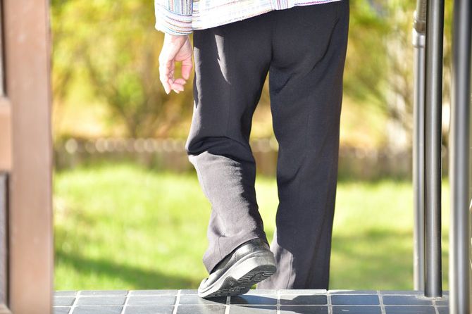 手すりをつかんで階段を下りているシニア女性