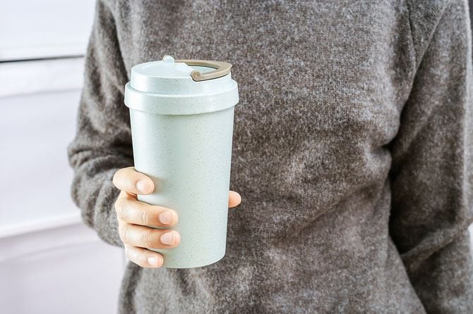 女の子は彼女の手に再利用可能なエココーヒーカップを保持しています