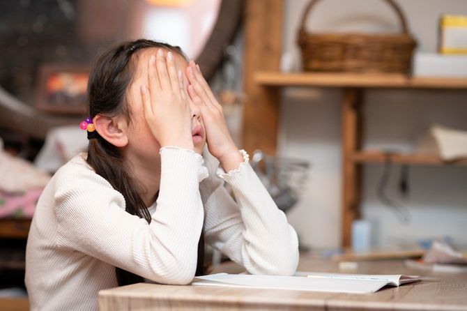 勉強中に顔を覆う子供