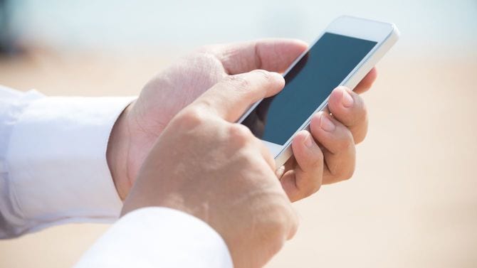 ビーチでスマホを使用している男性の手元