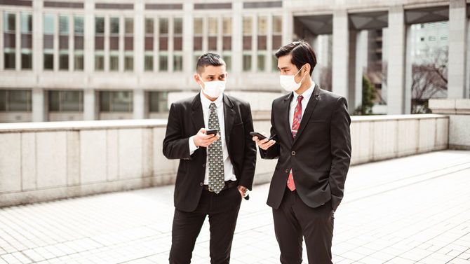 マスクを着けて話し合うビジネスパーソン