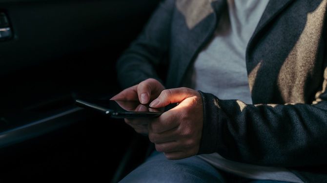 車の中でテキストメッセージを入力するビジネスウーマン、手をクローズアップ