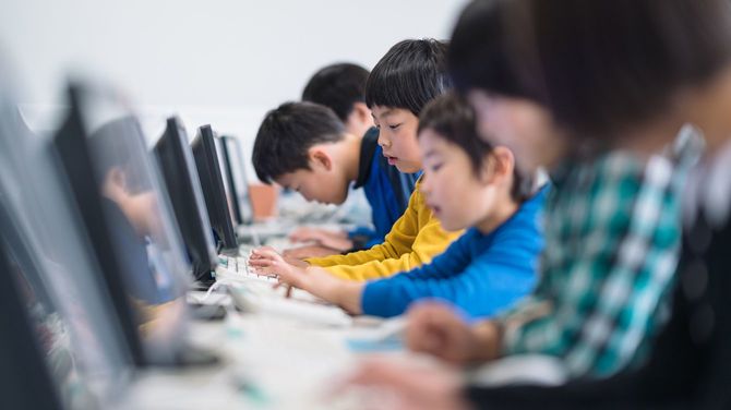 学校でコンピュータを使うことを学ぶ小学生のグループ