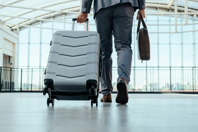 空港で荷物を持って歩く匿名のビジネスマン