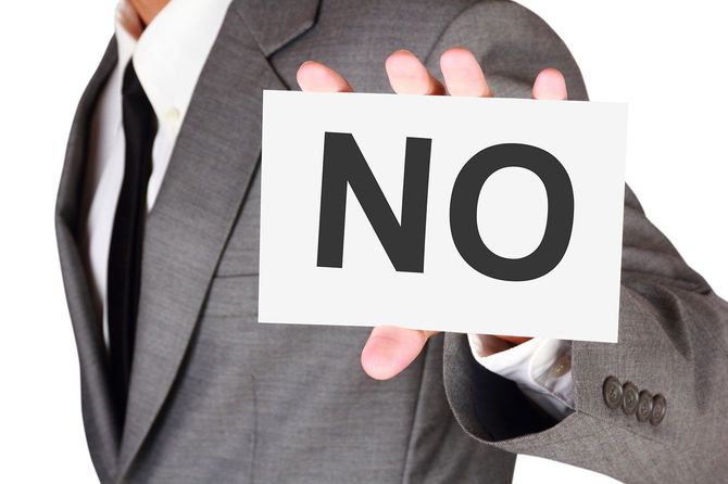 「NO」と書かれたカードを持つ人