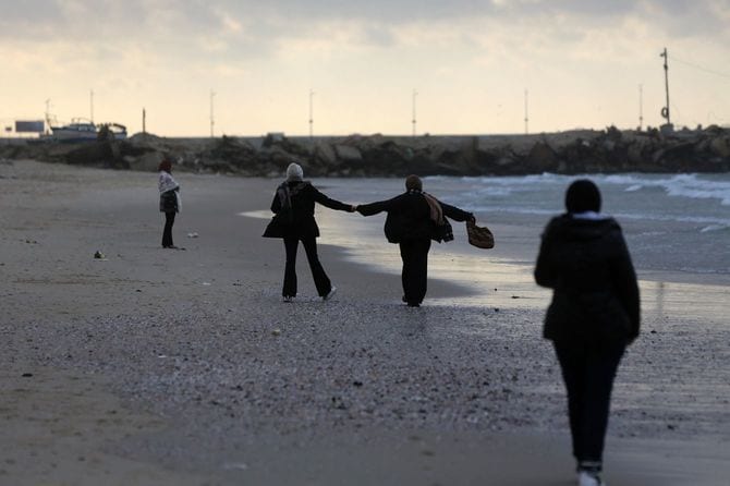 雨の日にガザ市のビーチに集まったパレスチナ人たち