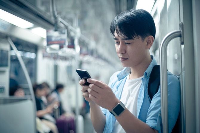 地下でスマートフォンを使用する若い男
