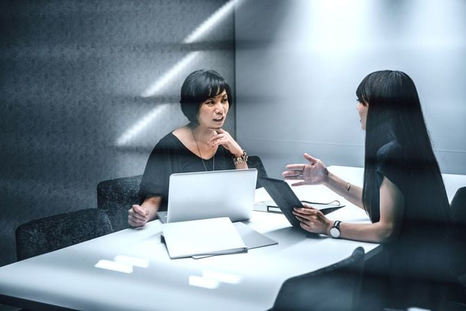 モダンなオフィス内で話し合う女性二人