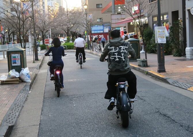 ヘルメット、ナンバープレート無しで走行する違法モペッドの男性（右）