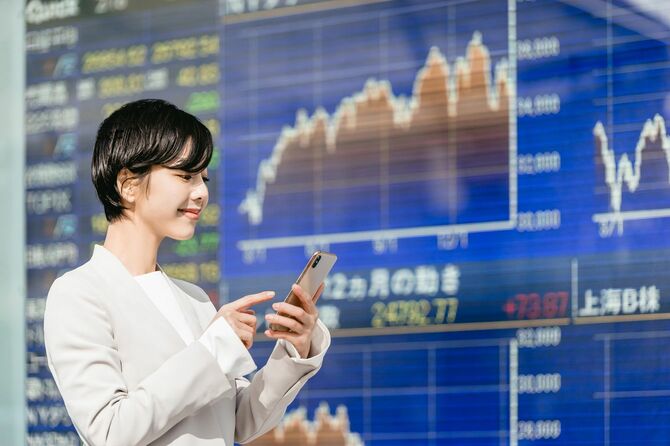 株式市場のボードを見ている女性