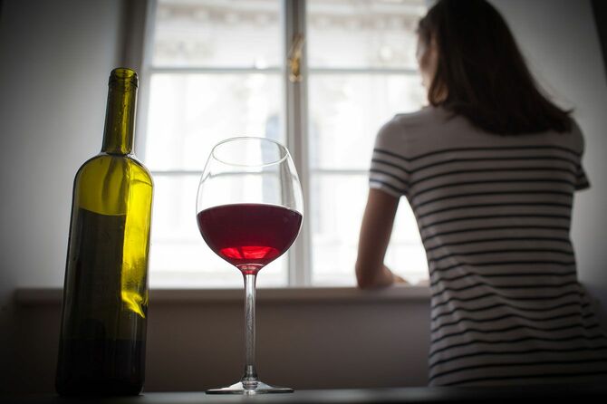 暗い部屋で一人ワインを飲んでいる女性