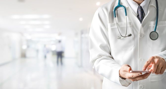 病院で携帯電話を使用している男性医師。メディカルヘルスケアとドクターサービス。