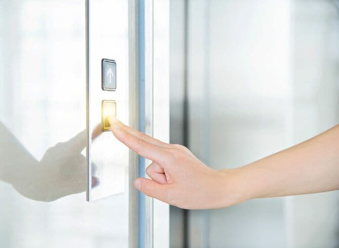 エレベーターのボタンを押す女性の手