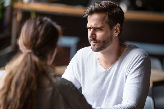 女性と向かい合って顔をしかめる男性