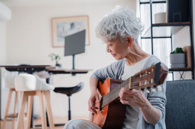 自宅でギターを弾くシニア女性