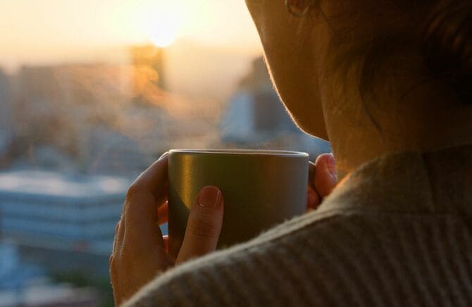 夕暮れの街を眺めながらコーヒーを飲む