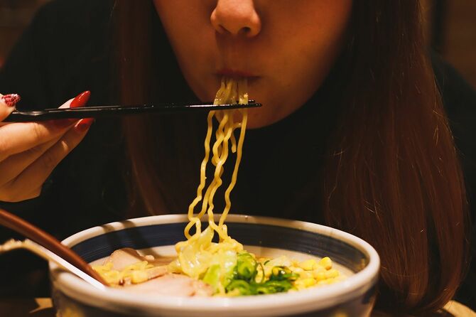 若いアジア人が北海道で日本の味噌ラーメンを食べている