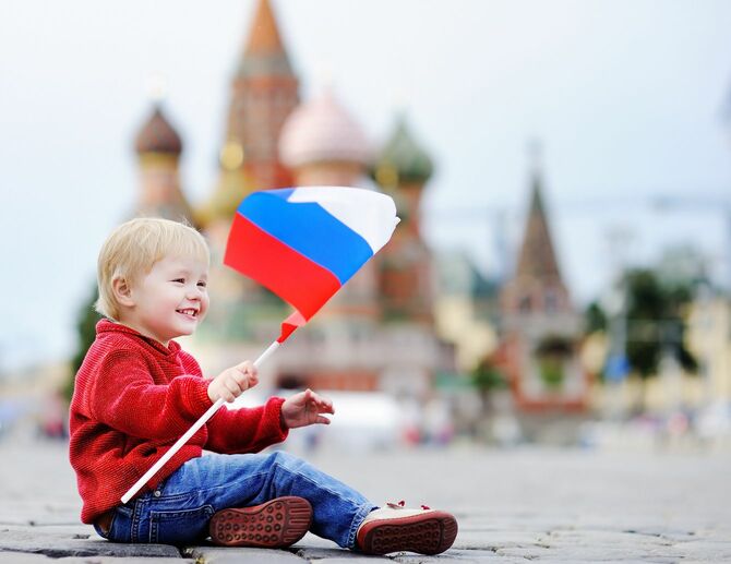 赤の広場を背景にロシアの旗で遊んでいる少年