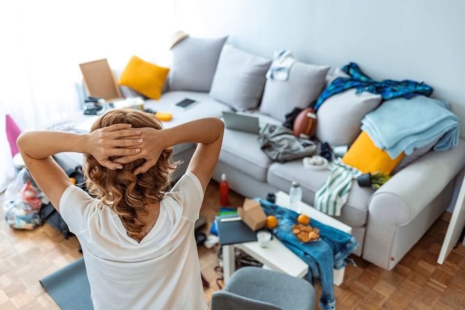 自宅で掃除の準備をしながら立っている成熟した主婦の背面図。