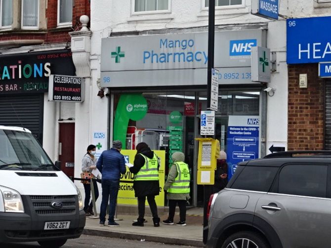 筆者が接種を受けた近所の薬局とその前で働くボランティアの人々