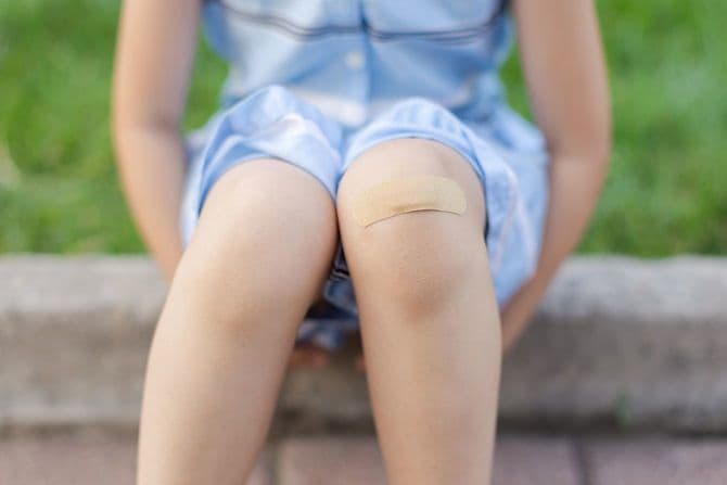 膝に絆創膏を貼った少女は腰を掛けて休んでいる