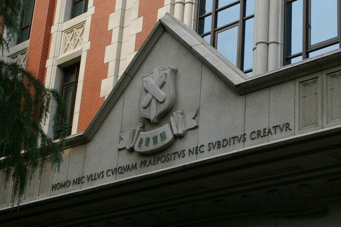 慶応義塾大学三田キャンパス東館正面に刻まれたロゴと文字「Homo nec ullus cuiquam praepositus nec subditus creatur」