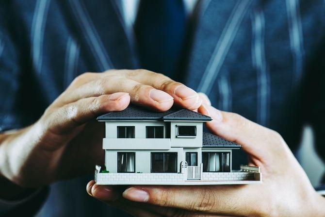 大事そうに家の模型を持っている男性の手元