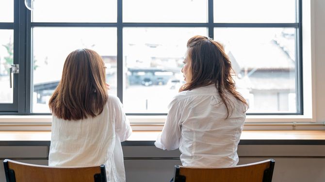 カフェの窓際の席に座り、会話する2人の女性