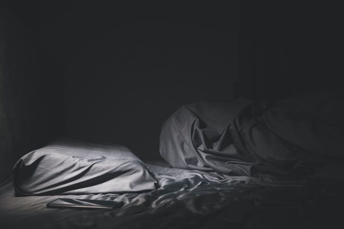 電気のついていない暗い部屋で人のいないベッド