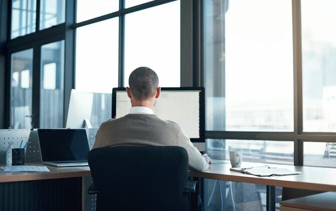 デスクワークをするビジネスマンの背面図