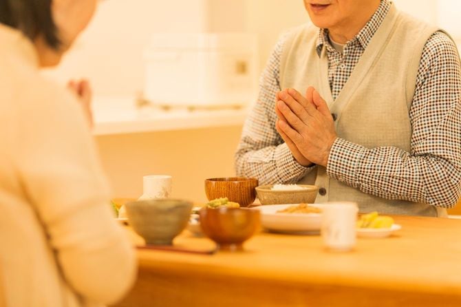 ご飯を前に手を合わせる老夫婦