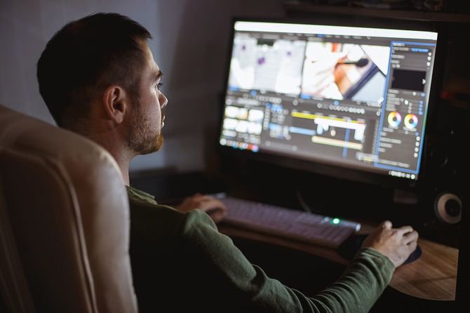 自宅デスクでPCを用い作業するビデオ編集者