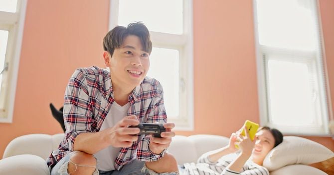 ゲームに夢中な男性とスマホに夢中な女性のカップル
