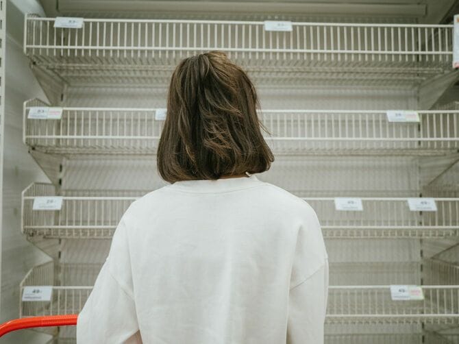 空っぽの商品棚を見る女性