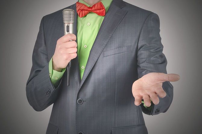 マイクを持ってスピーチをするちょうネクタイの男性