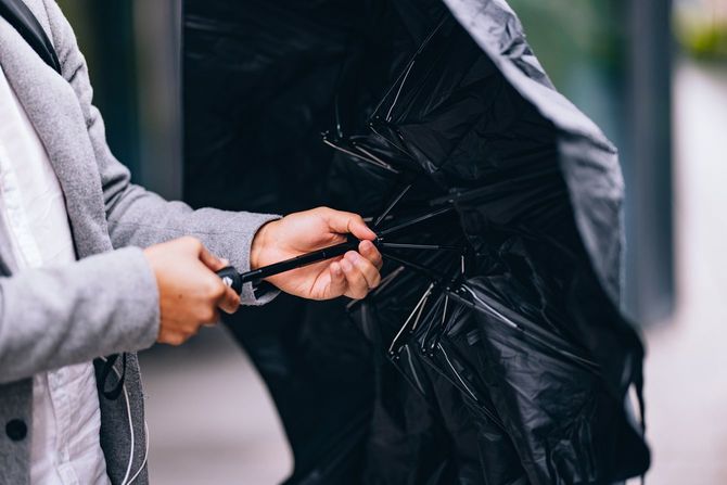 雨の日に傘を広げるビジネスパーソン