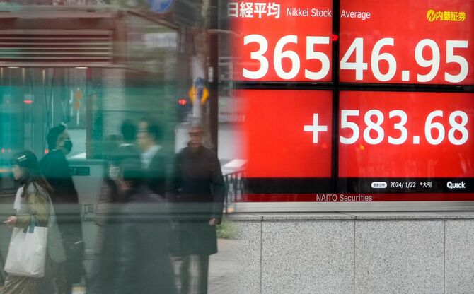 2024年1月22日、東京の株式市場表示板の前を通り過ぎる人々。日銀の金融政策継続への期待に押され、3万6000円の大台を突破した。
