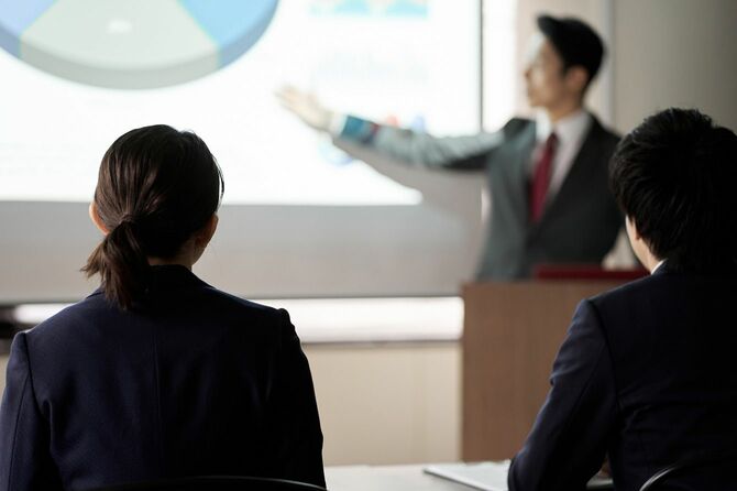 会議でプレゼンテーションを聞くビジネスパーソン