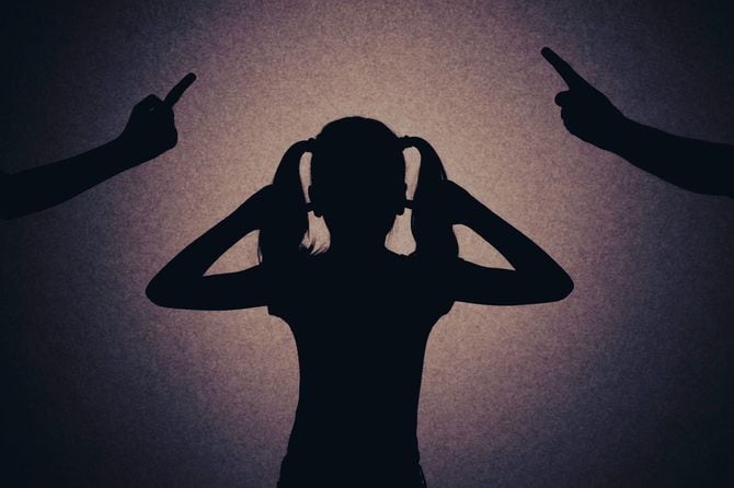 ののしり合いのけんかをする両親の間で耳をふさぐ少女