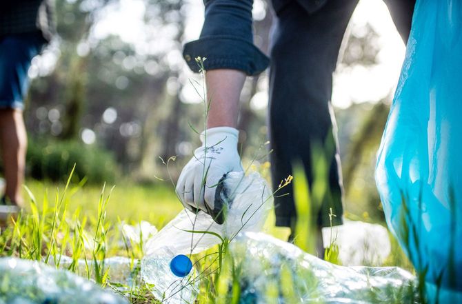 森に落ちているゴミを拾う男性の手