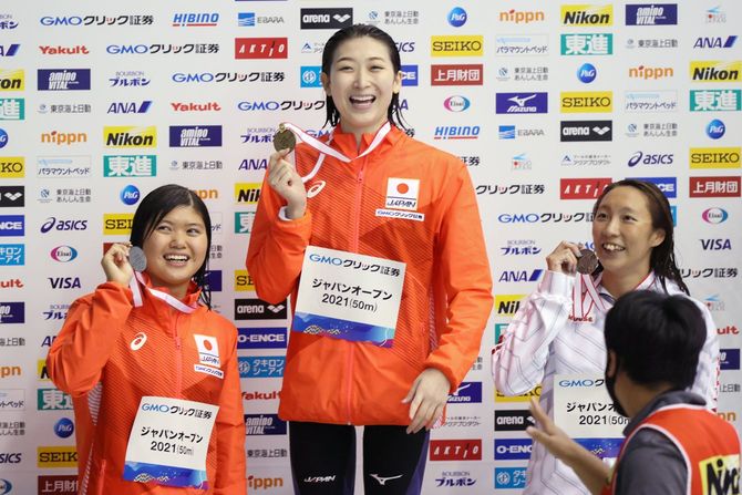 女子100メートルバタフライで優勝し笑顔を見せる池江璃花子(中央、ルネサンス)。左は2位の長谷川涼香(東京ドーム)、右は3位の相馬あい(ミキハウス)=6日、千葉県国際総合水泳場