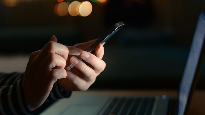 深夜にスマホとノートパソコンを使用している女性の手元