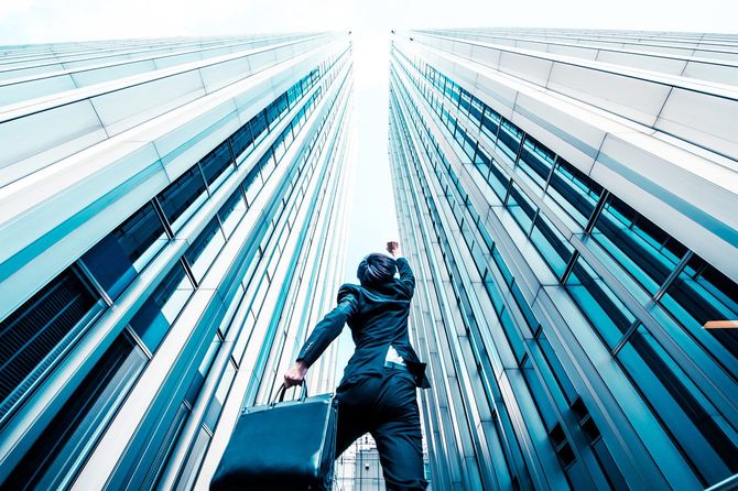 高層ビルの谷間でこぶしを突き上げるビジネスマン