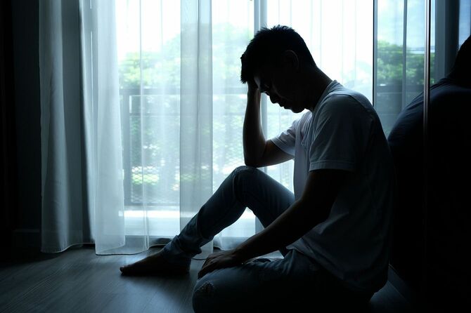 暗い部屋で頭を抱えて座る男性