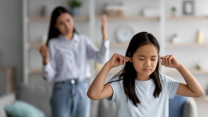 耳を覆う怒ったアジアの女の子